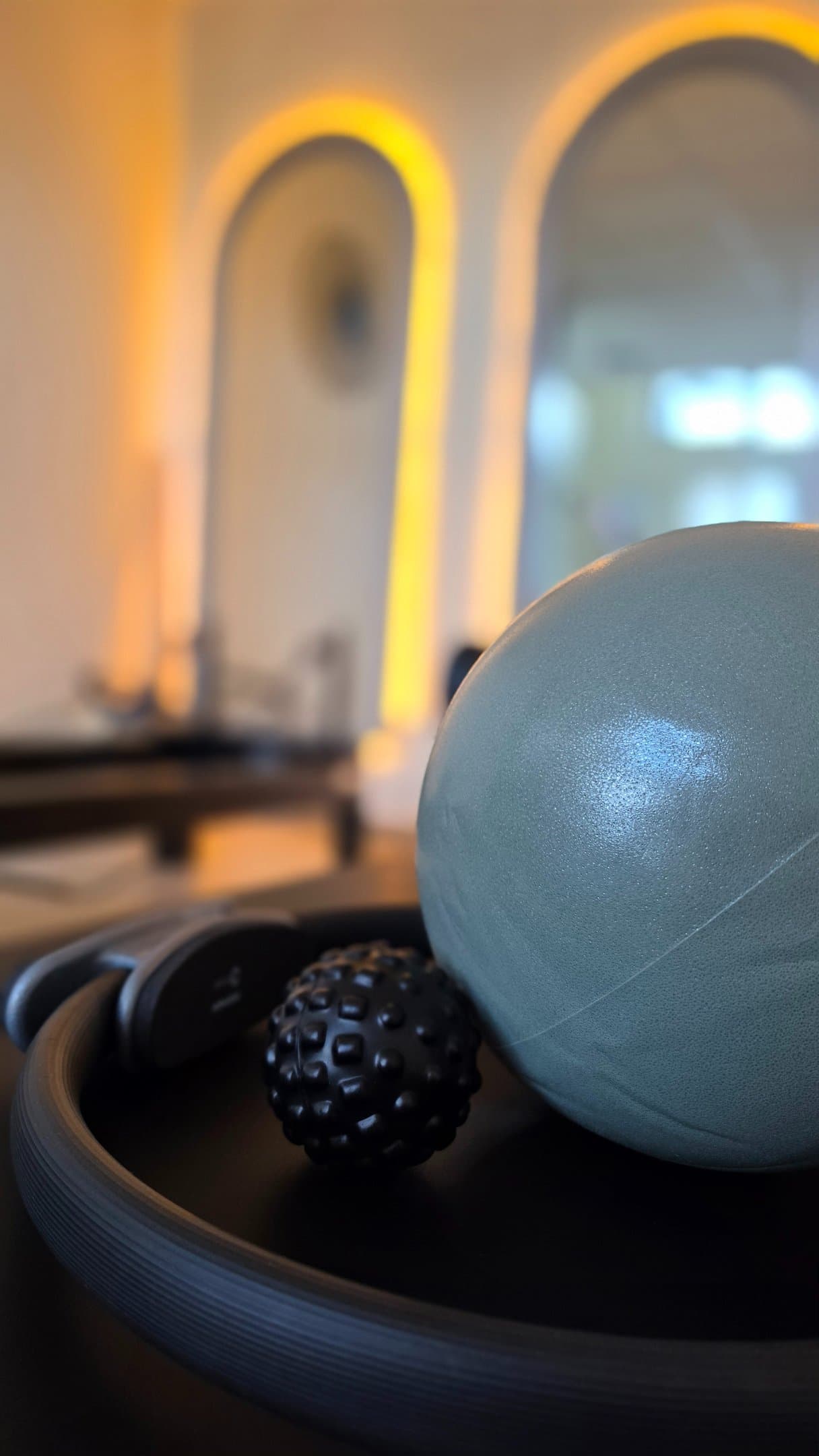 Pilates lopta, masažna loptica i obruč, u pozadini osvijetljena zrcala